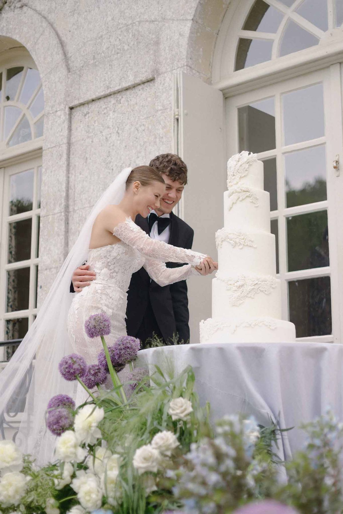 Bride and groom cutting wedding cake at outdoor stone venue terrace