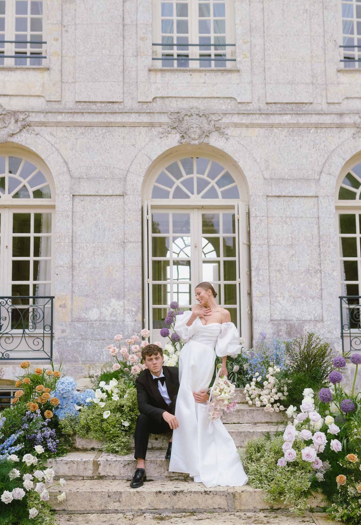 Bride and groom portrait with floral installations on French château stone steps