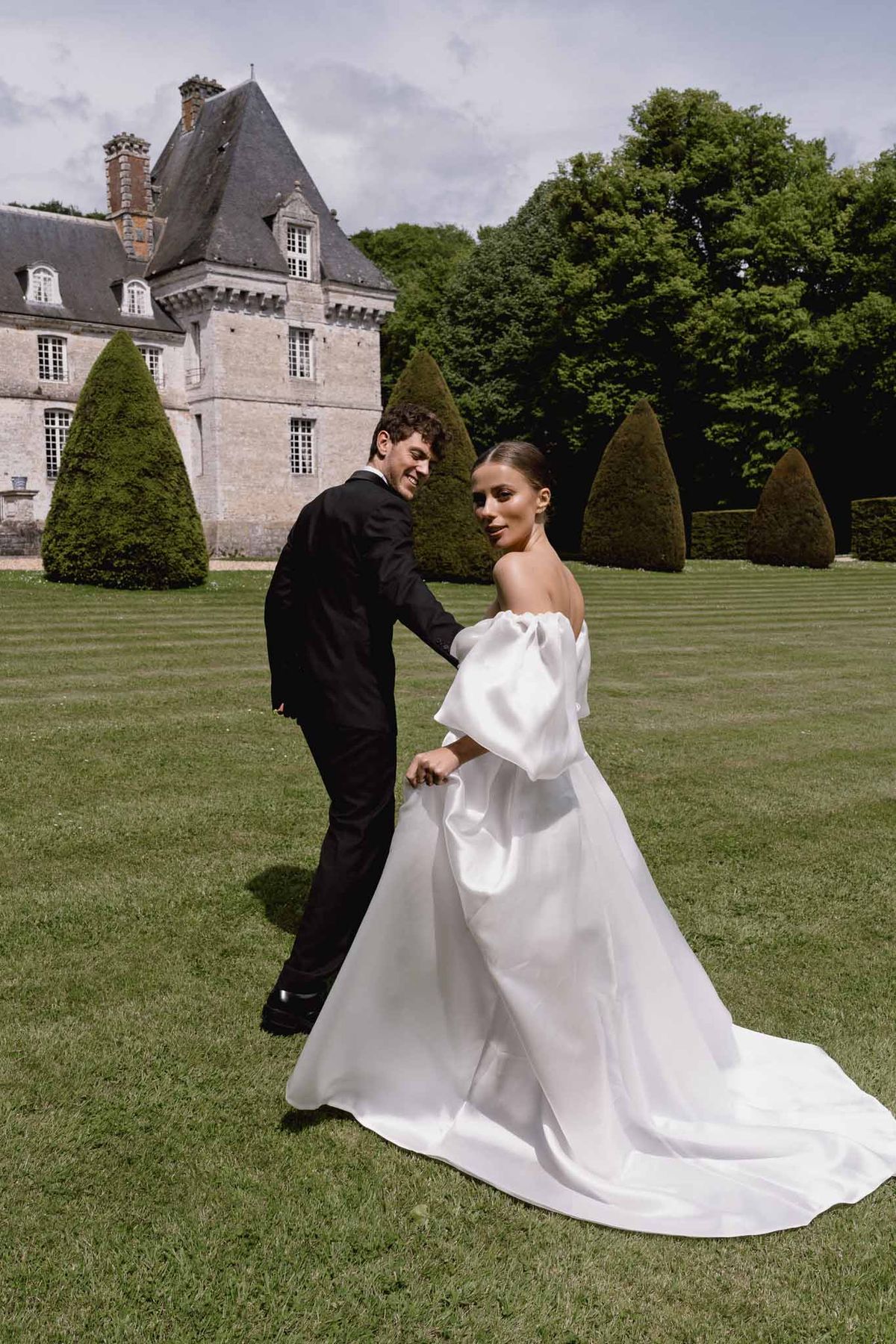 Bride and groom portrait session on château lawn with formal gardens