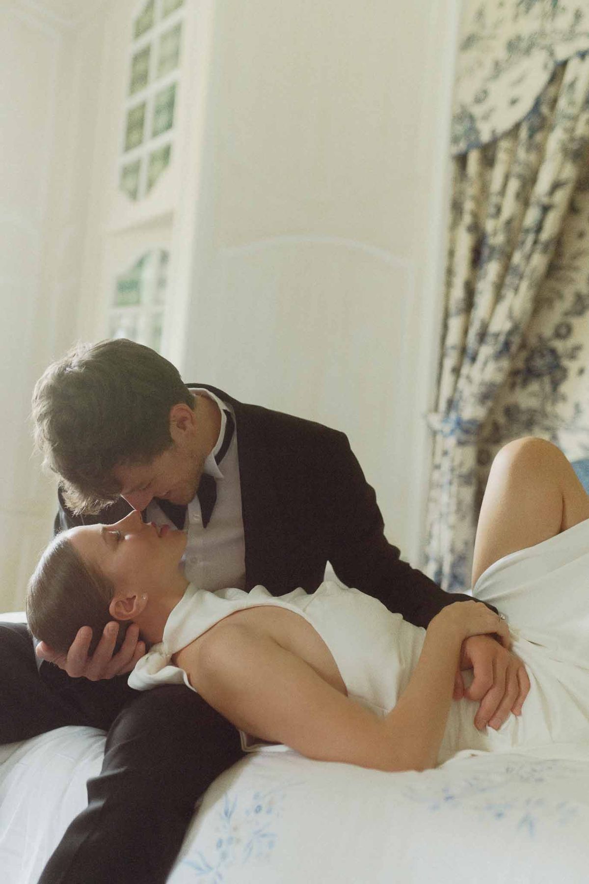 Bride and groom sharing intimate kiss in bridal suite bedroom