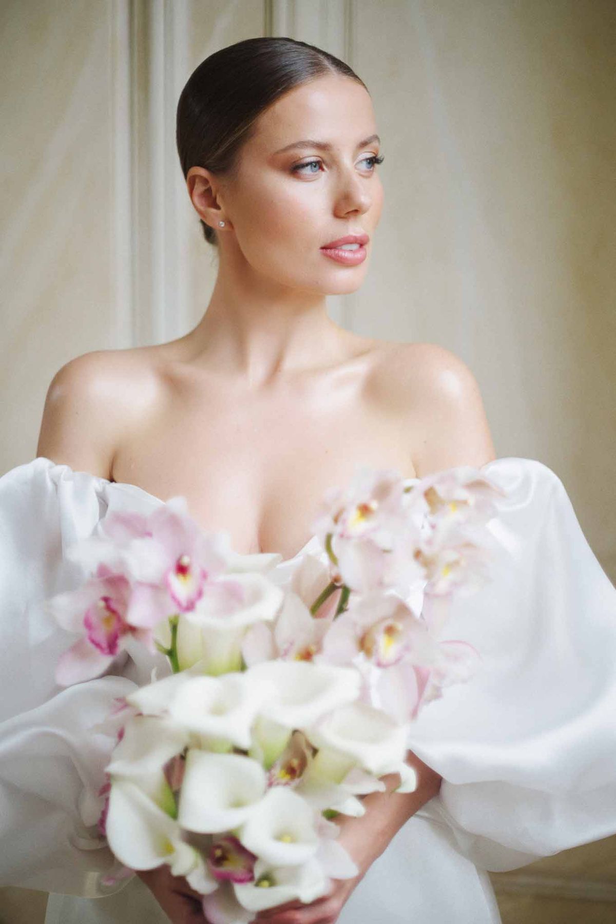 Bride holding white and pink orchid bouquet in minimalist indoor setting