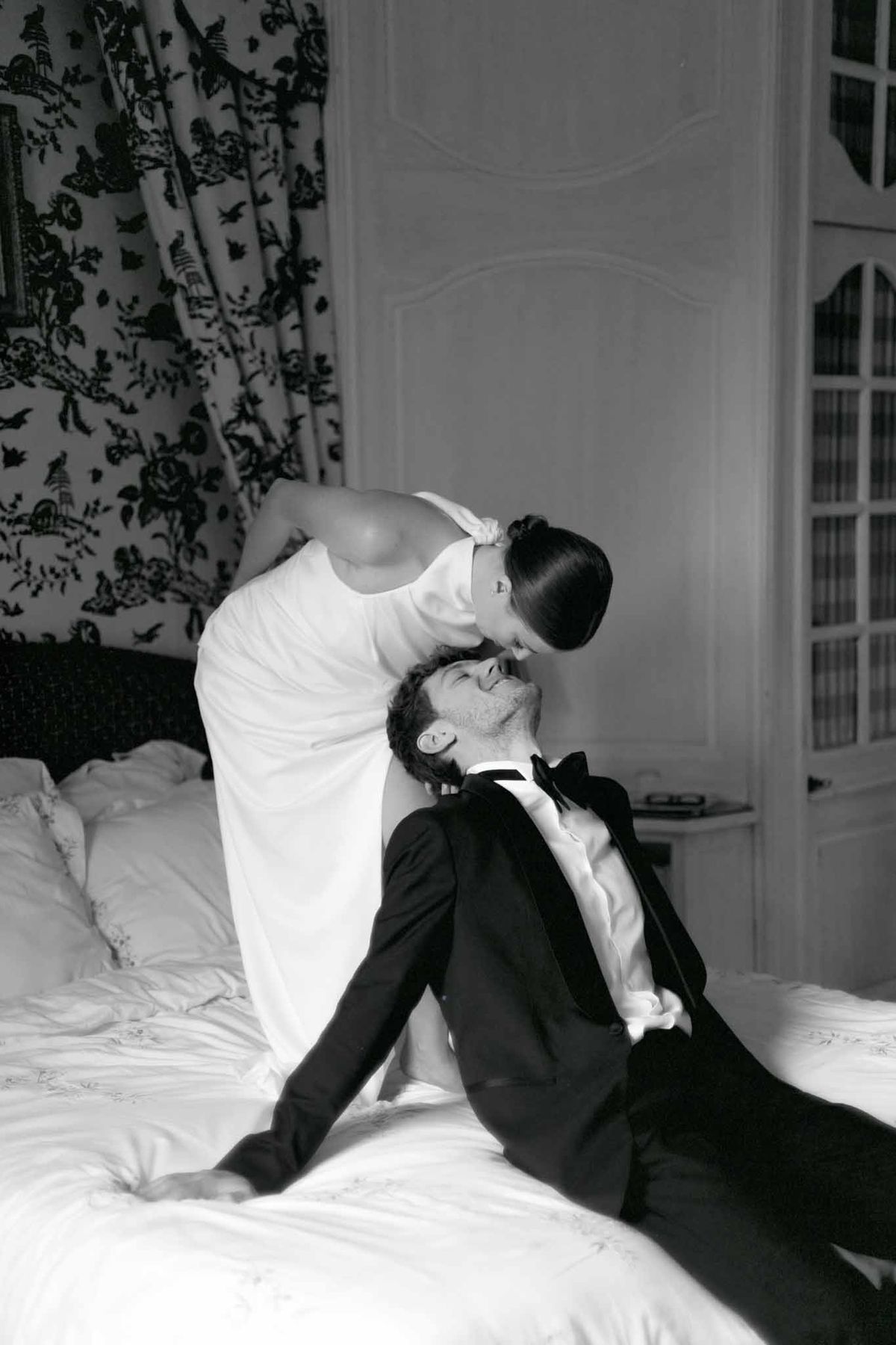 Bride and groom intimate portrait in elegant bedroom with French doors and botanical curtains