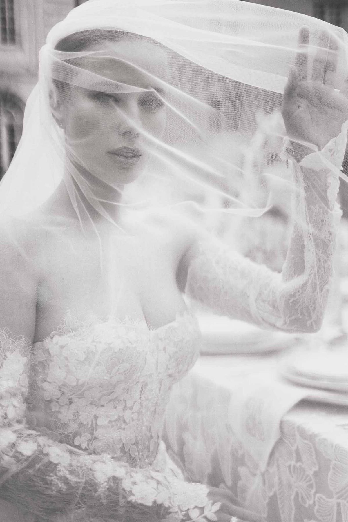 Black and white bridal portrait with layered tulle veil and ornate lace wedding dress indoors