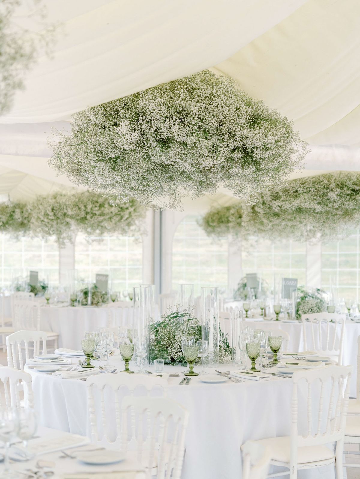 White marquee reception with suspended gypsophila cloud installations and green hobnail glassware