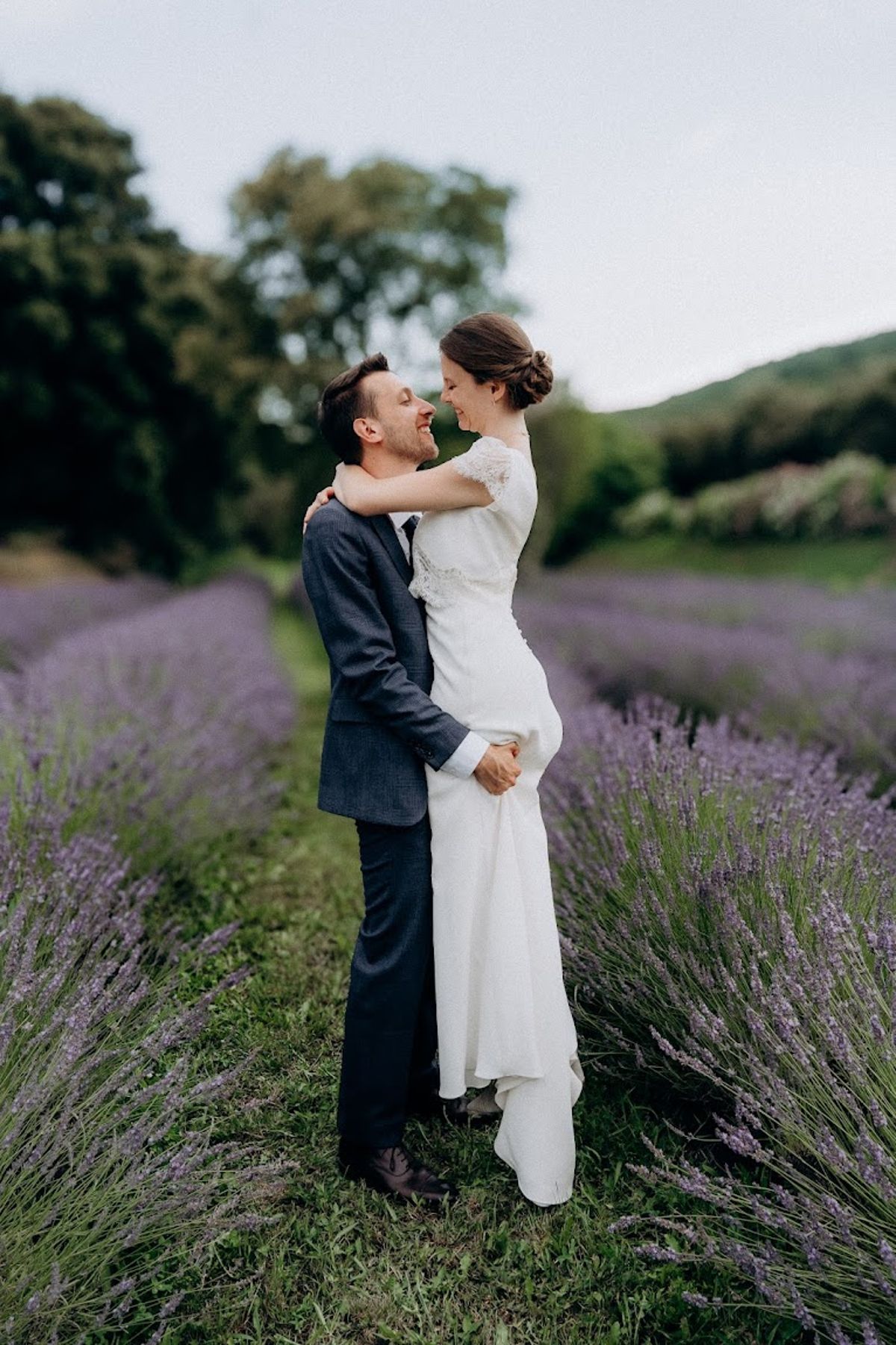 Groom lifts bride in ivory lace gown in a blooming Provence lavender field