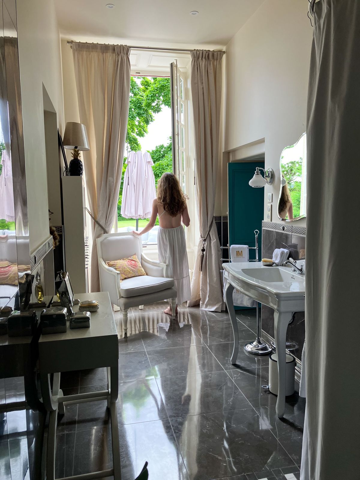 Getting-ready suite with vanity marble bathroom pedestal sink and open French doors to garden