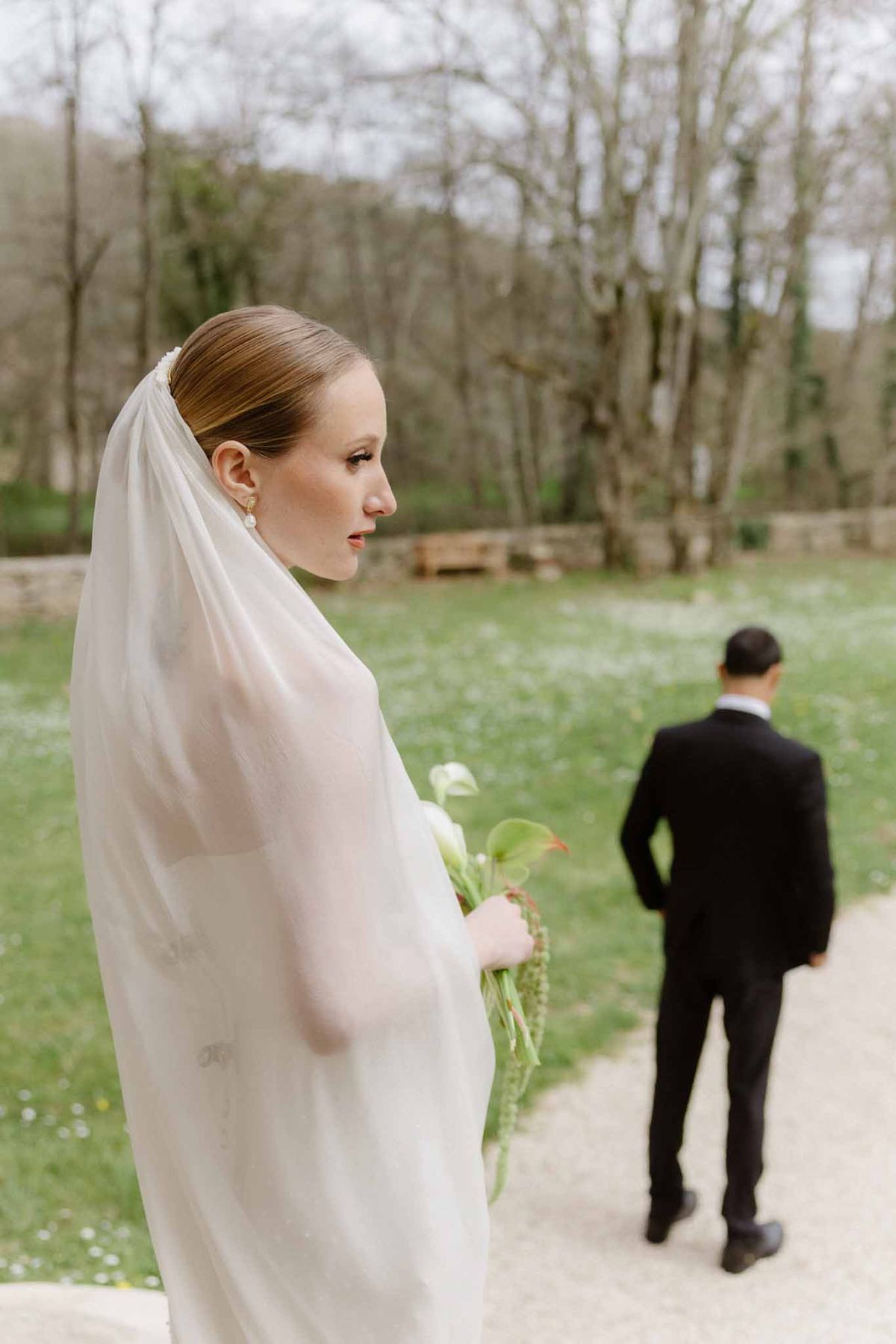 Bride in ivory dress and veil during first look moment with groom in outdoor garden setting