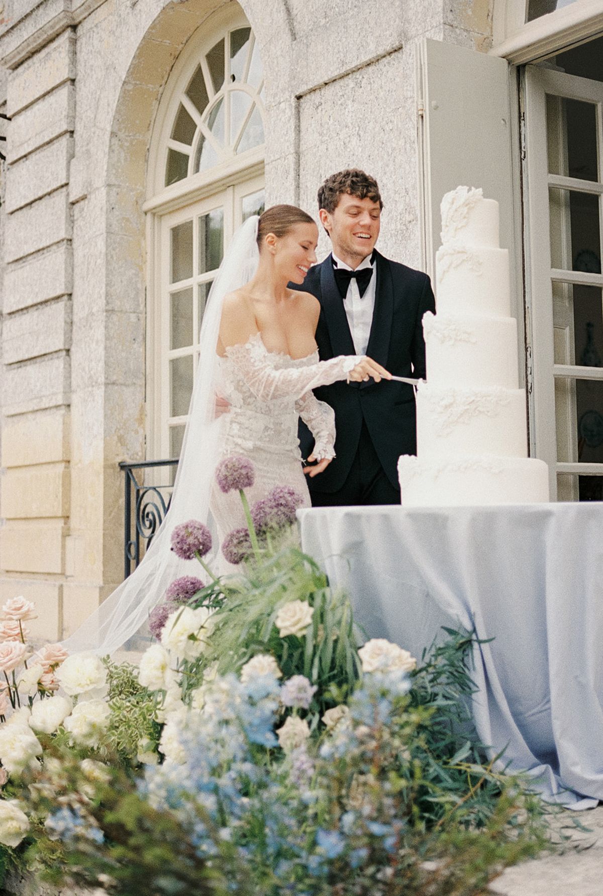 Bride and groom cutting wedding cake at classical stone courtyard venue