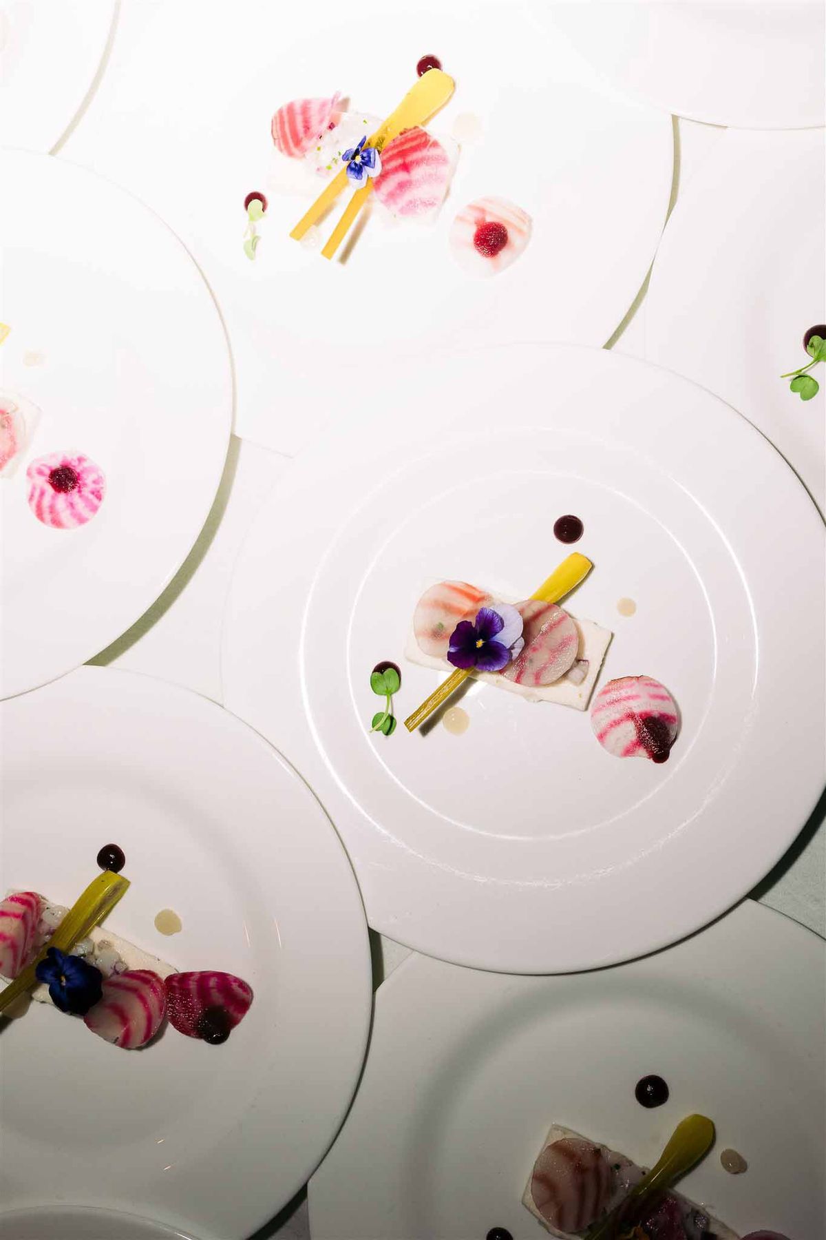 Overhead flat lay of wedding place settings with floral arrangements and gold utensils on white plates