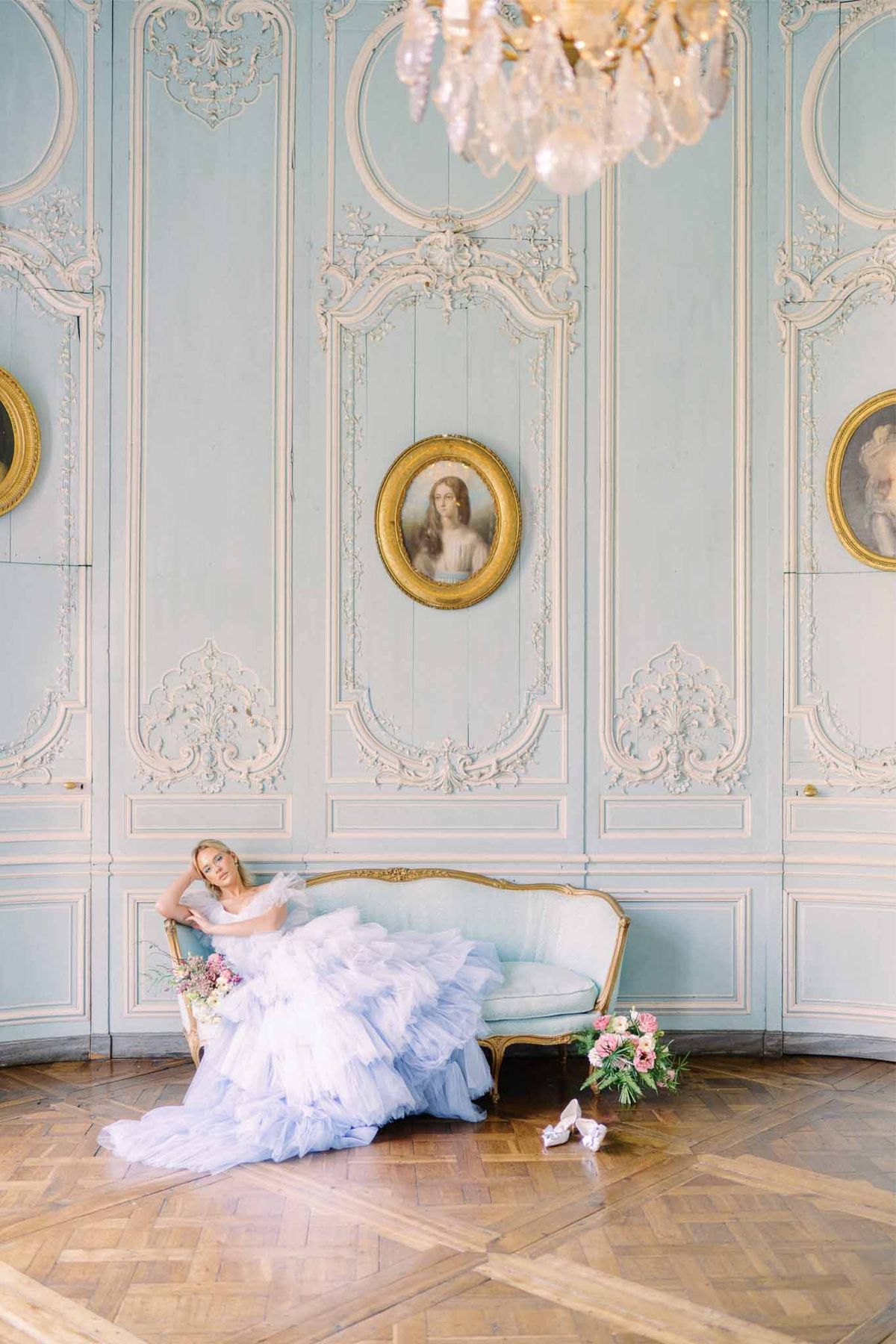 Bride in lavender ball gown on gilded settee in ornate palace interior with rococo architectural details
