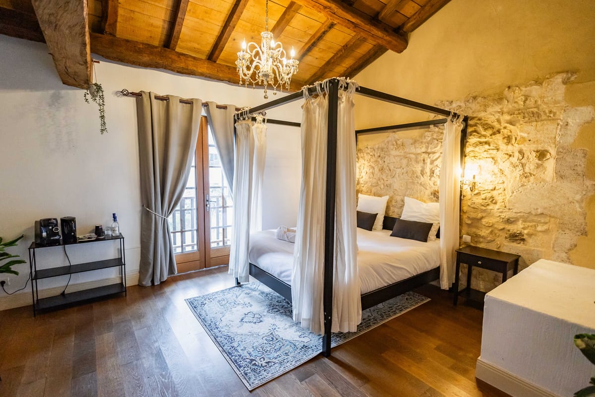 Stone-walled bedroom suite with four-poster bed crystal chandelier and dark wood beams