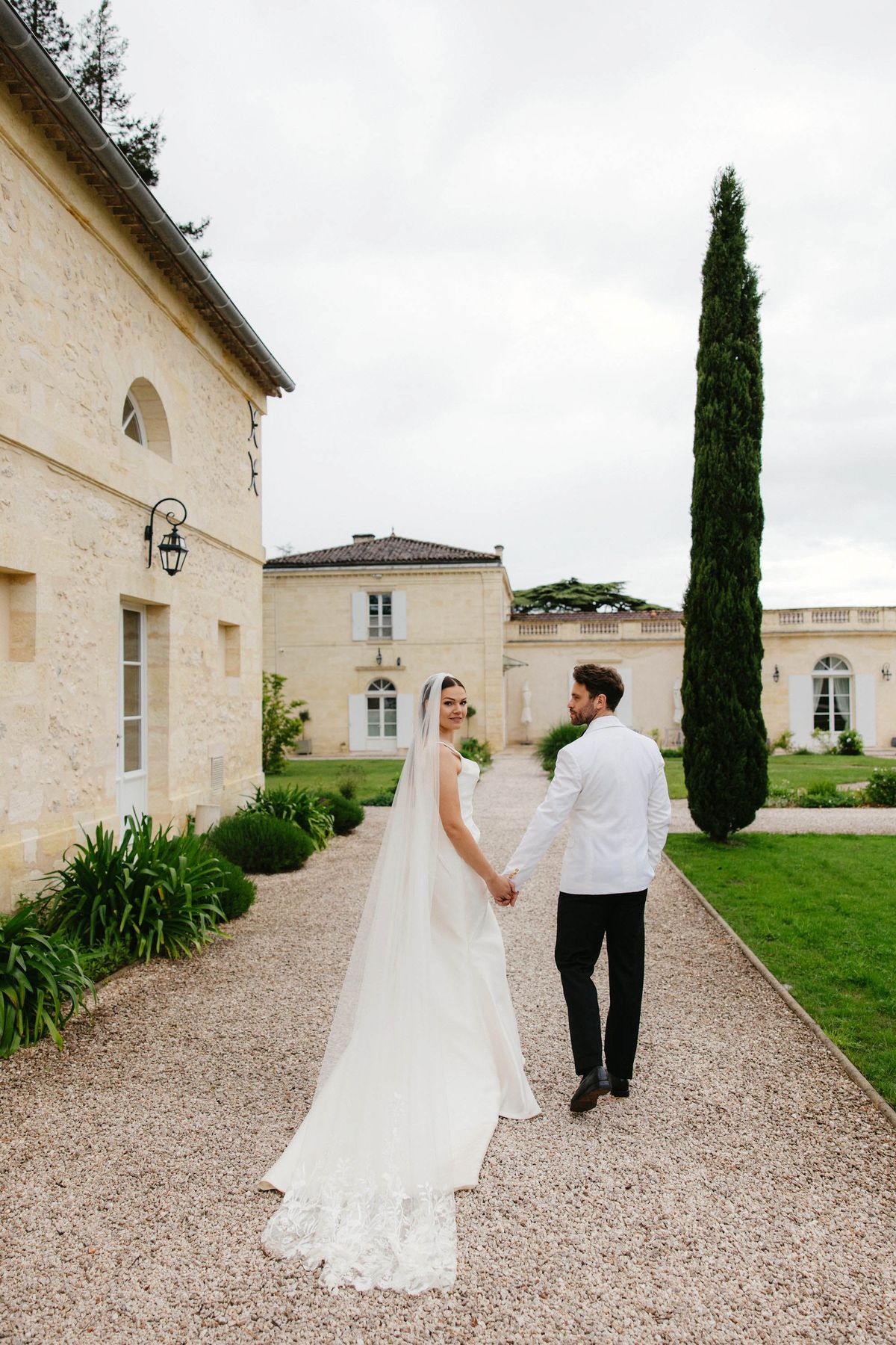 Bride and groom walking hand-in-hand in courtyard of French chateau estate