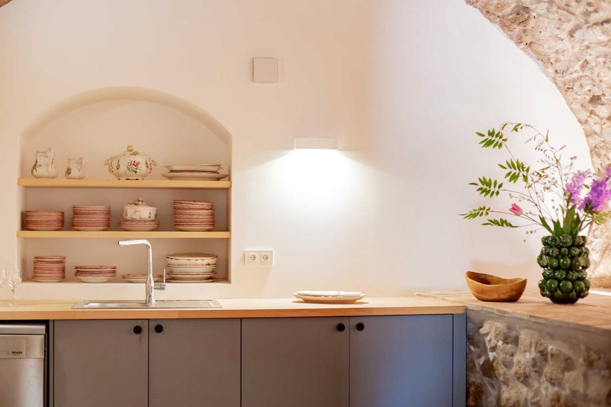 Venue kitchen with grey cabinetry, arched niche shelving with floral china, and pineapple vase