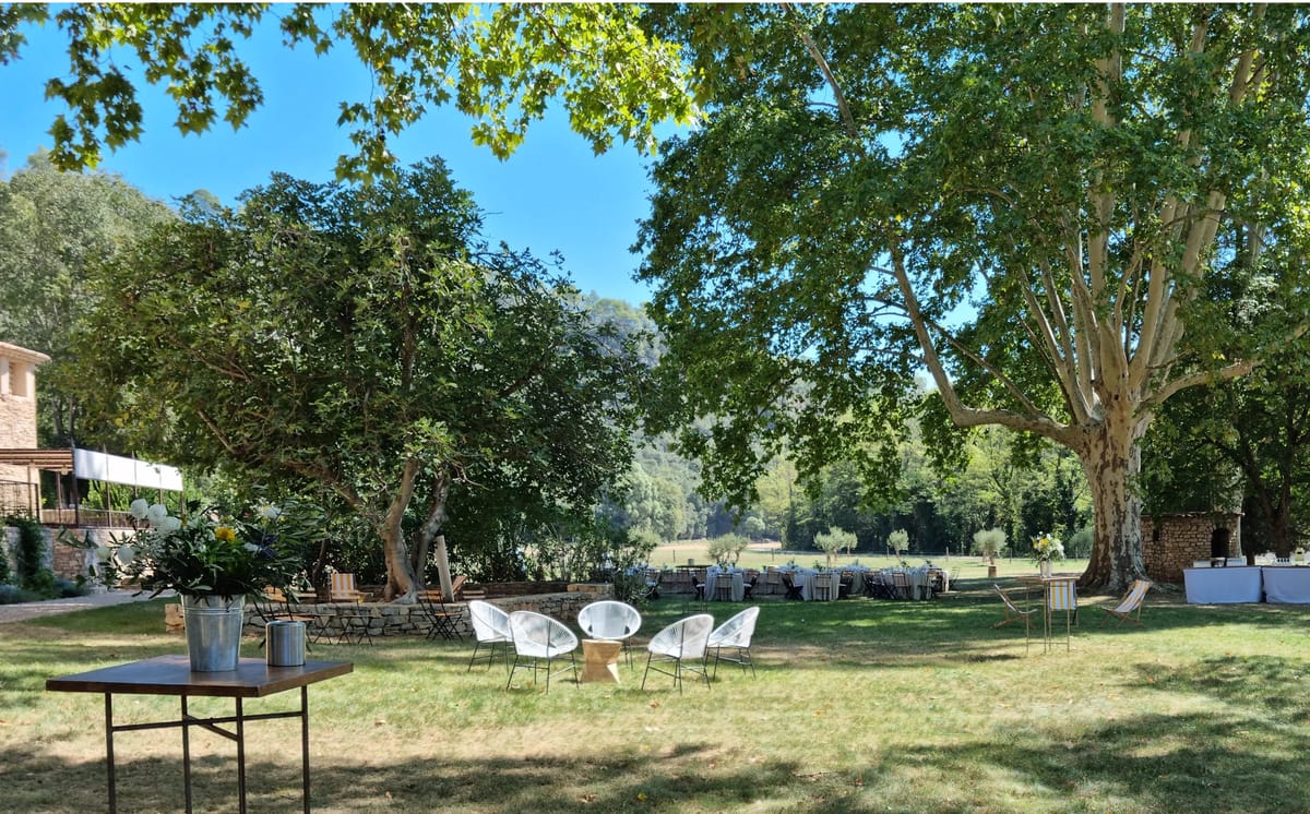 Outdoor reception with white wire chairs, yellow deckchairs, and round tables on Provencal bastide lawn