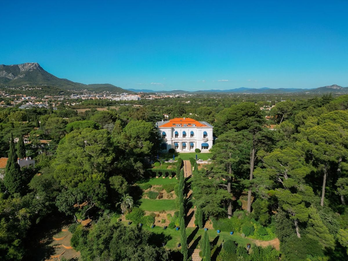 Aerial panorama of villa and gardens with mountain backdrop at Domaine Rocabella, French Riviera