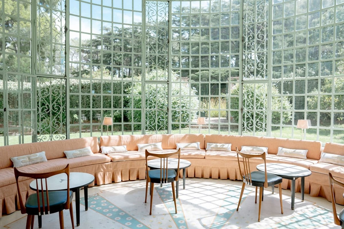 Conservatory lounge with iron window wall and garden views at Domaine Rocabella, French Riviera
