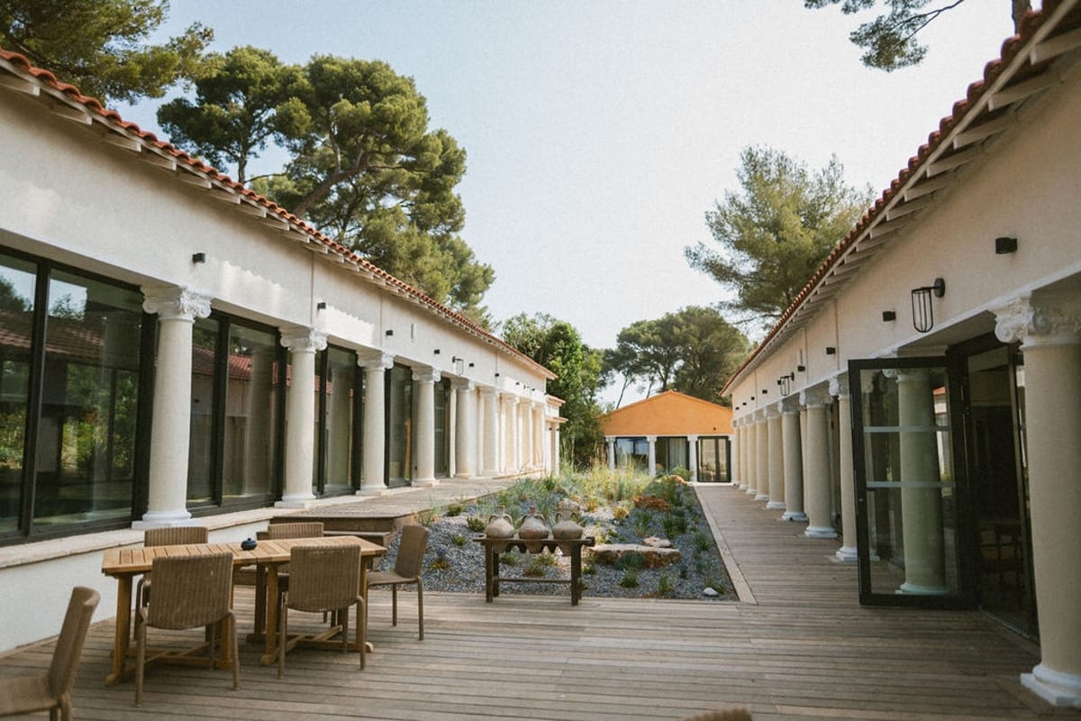 Colonnaded courtyard terrace with timber deck and dining areas at Domaine Rocabella, French Riviera