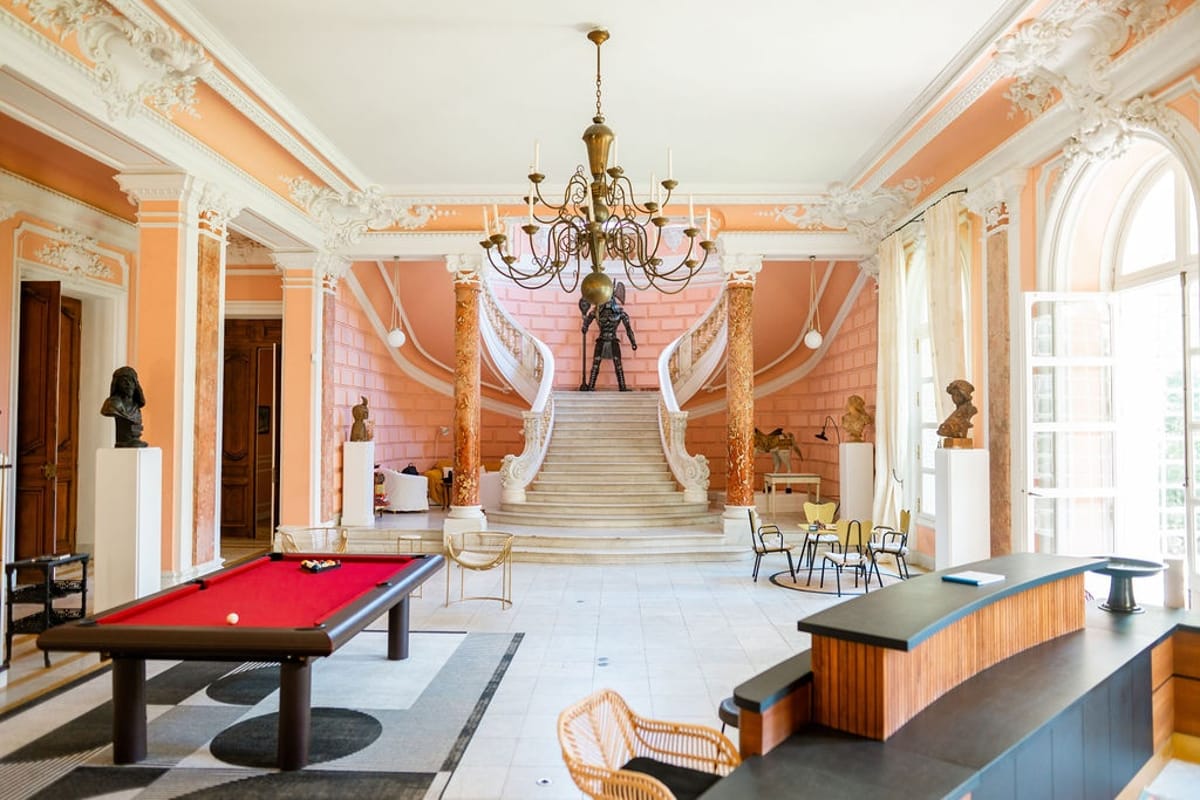 Grand hall with chandelier, double staircase, and billiard table at Domaine Rocabella, French Riviera