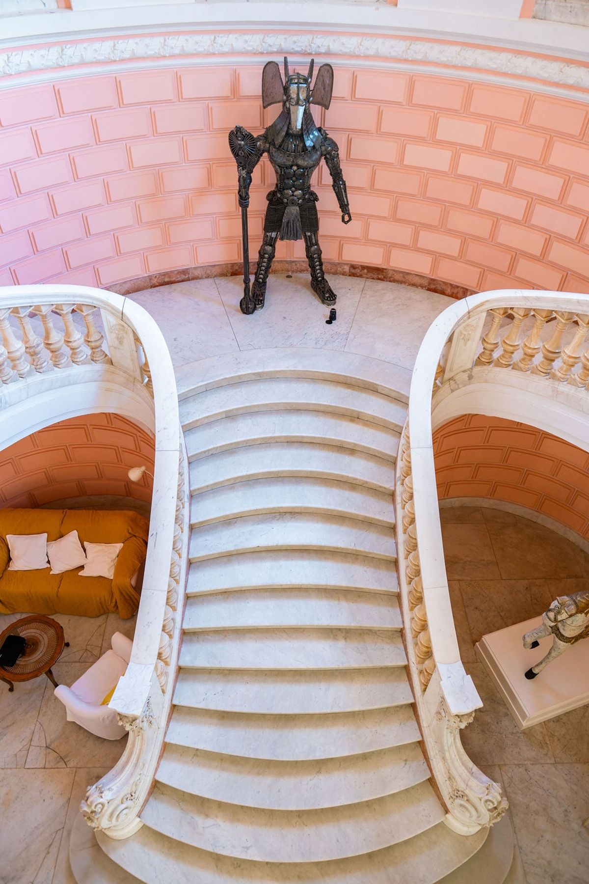 Grand marble double staircase with pink walls and knight sculpture at Domaine Rocabella, French Riviera