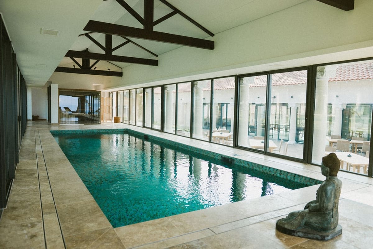 Indoor lap pool with Buddha statue and glass walls at Domaine Rocabella, French Riviera