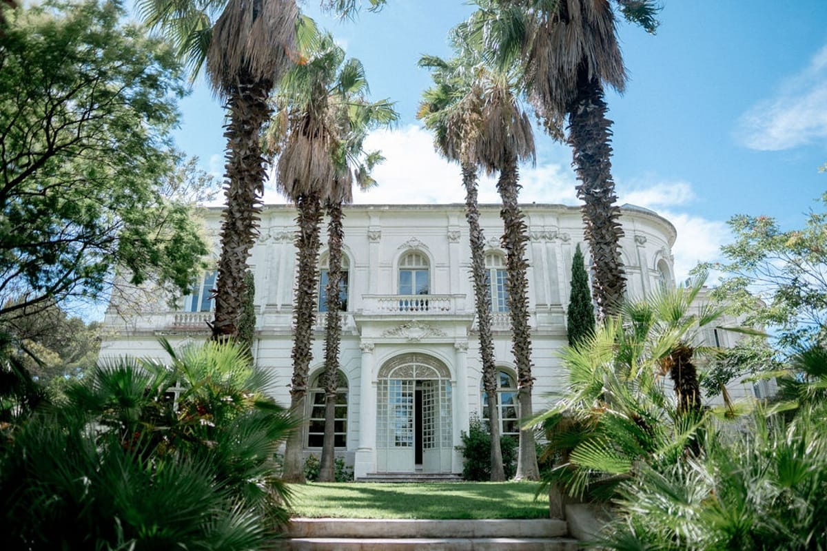 Belle Epoque villa facade with palm trees and gardens at Domaine Rocabella, French Riviera