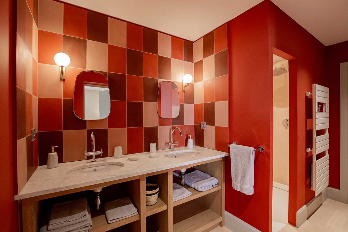 Modern retro bathroom with terracotta checkerboard tiles, double oak vanity, and red-tinted mirrors