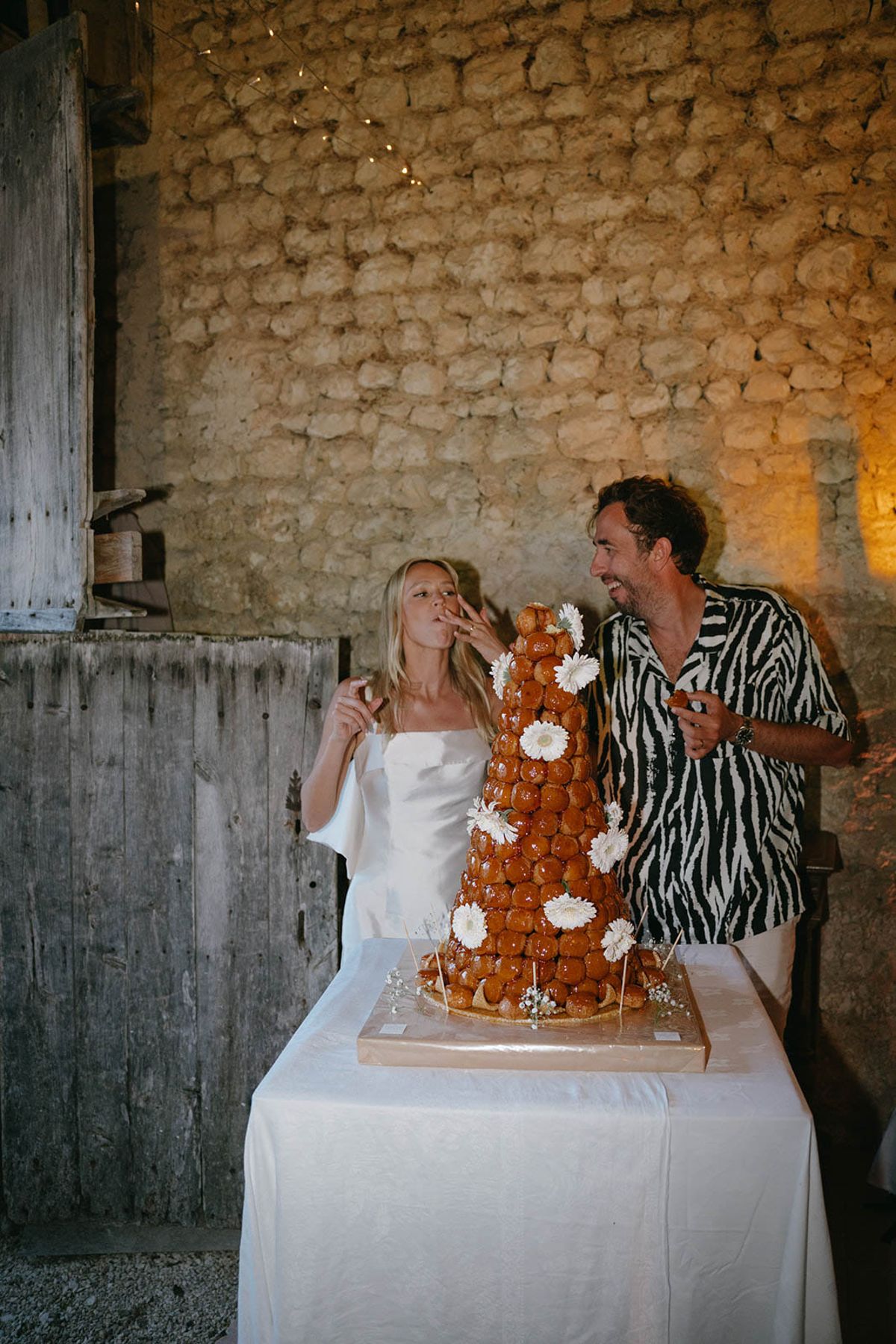 Bride and groom cutting croquembouche wedding cake at intimate indoor reception