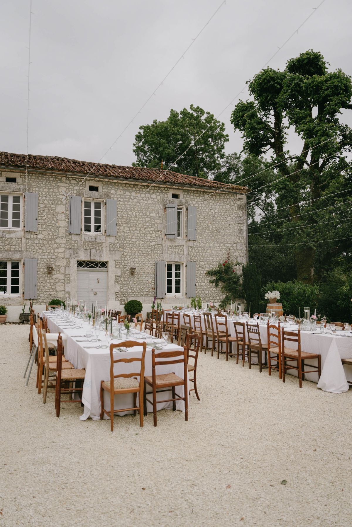 Reception table setup with white linens and terracotta planters at stone château courtyard