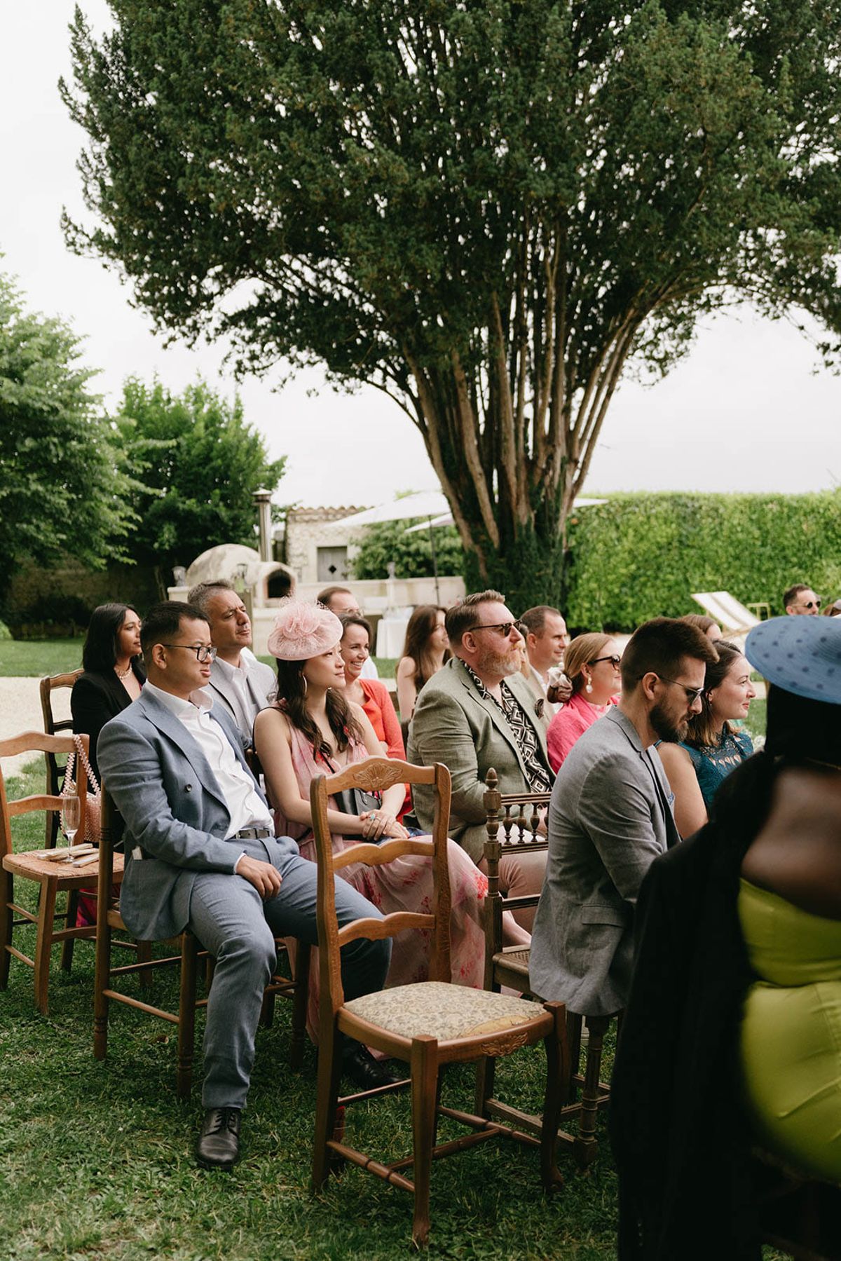 Outdoor wedding ceremony with guests seated in wooden chairs in Mediterranean garden setting