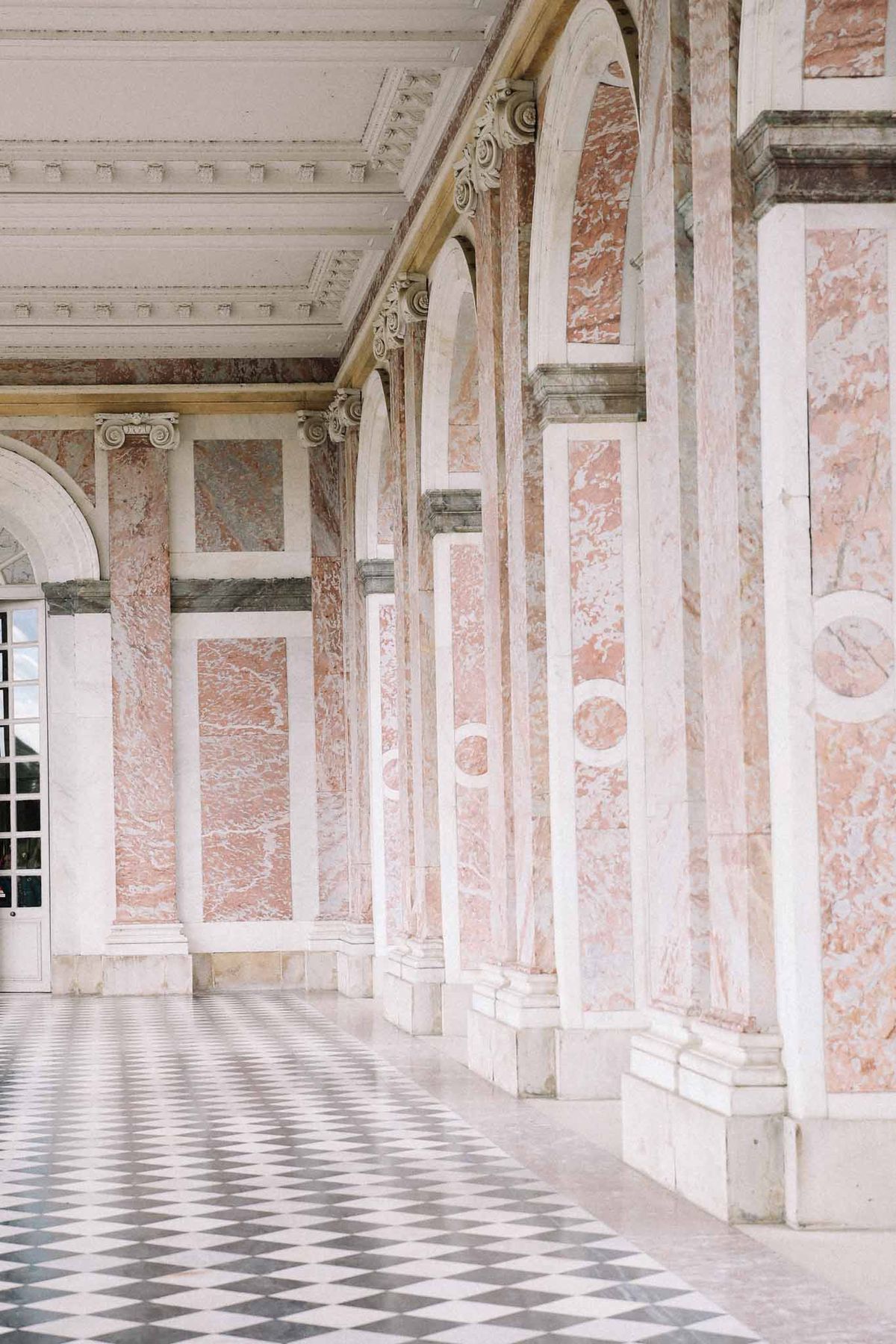 Classical covered corridor with Corinthian columns and ornate ceiling at elegant wedding venue