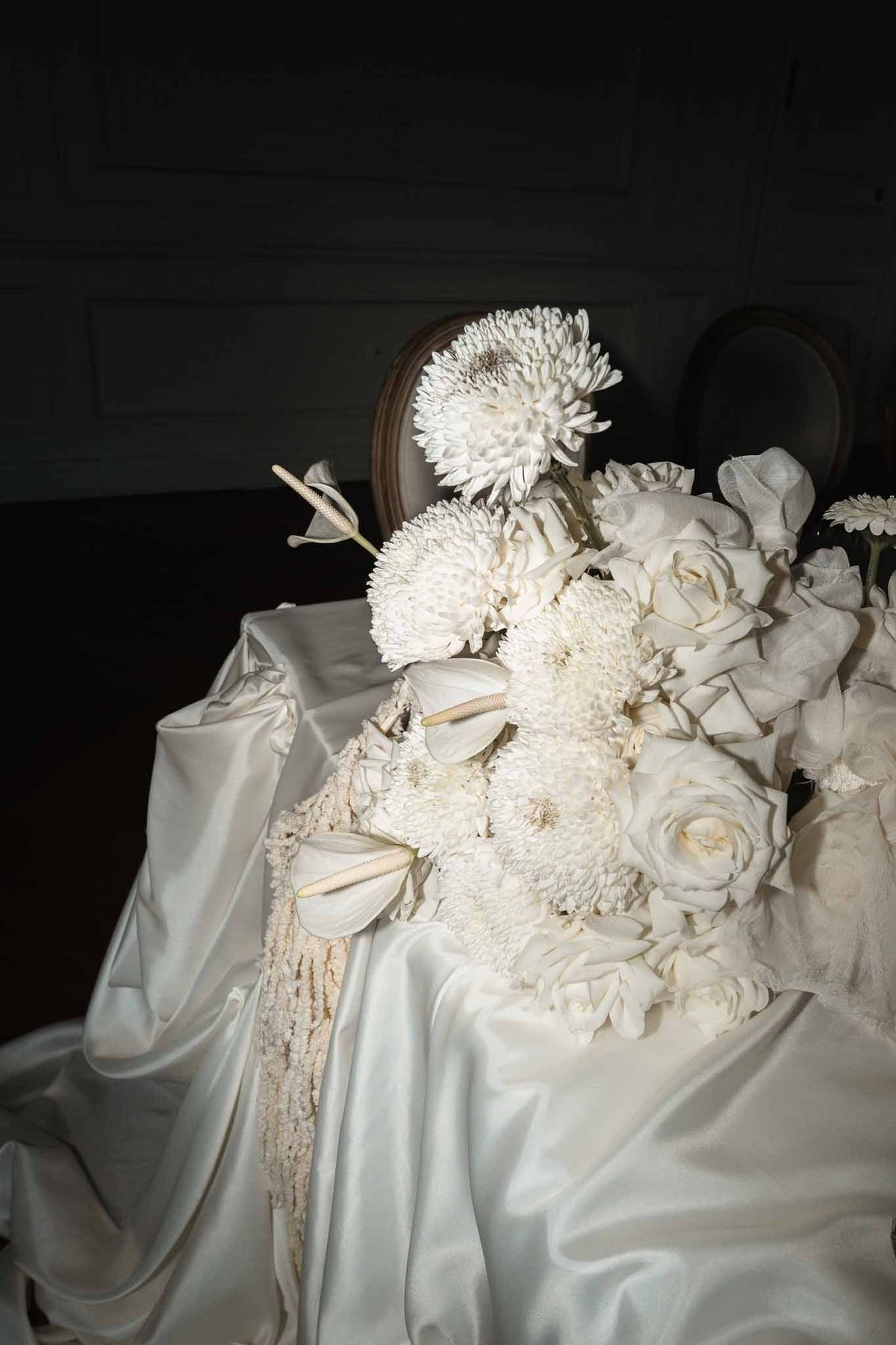 White dahlia and garden rose bridal bouquet with champagne ribbon on ivory silk fabric