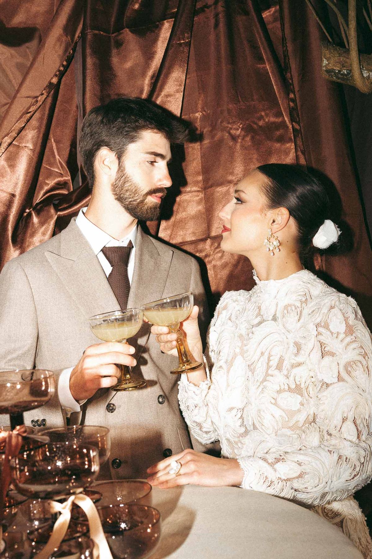Bride and groom sharing champagne toast during wedding reception with velvet backdrop