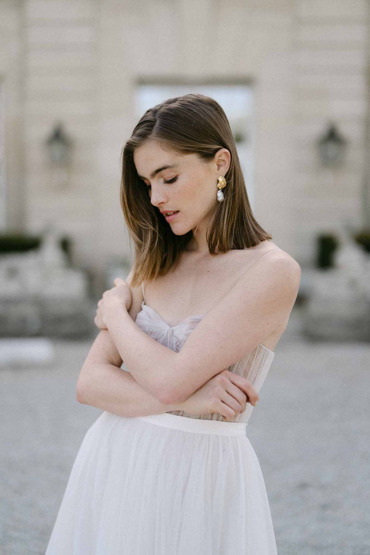 Bride in lavender and ivory gown with pearl earrings at modern architectural venue
