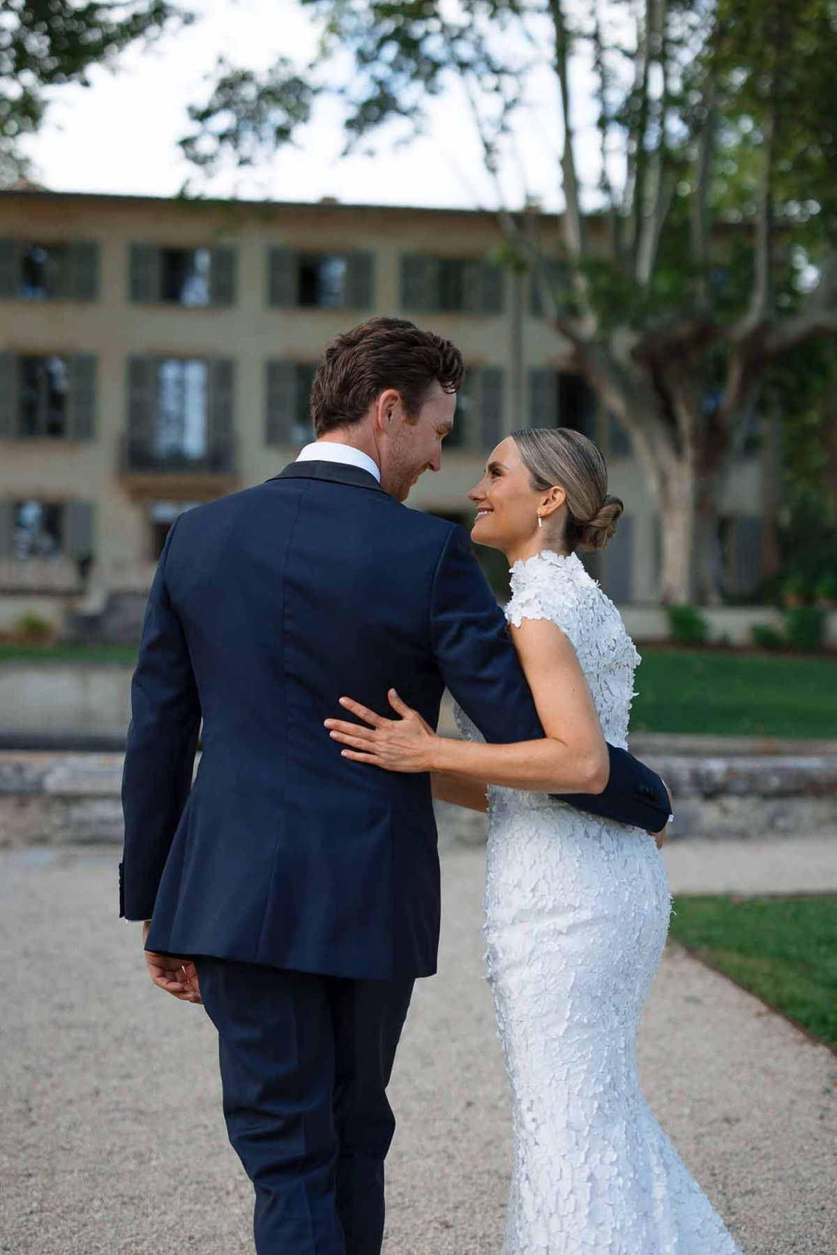 Bride and groom intimate portrait in European courtyard with stone building and pine trees