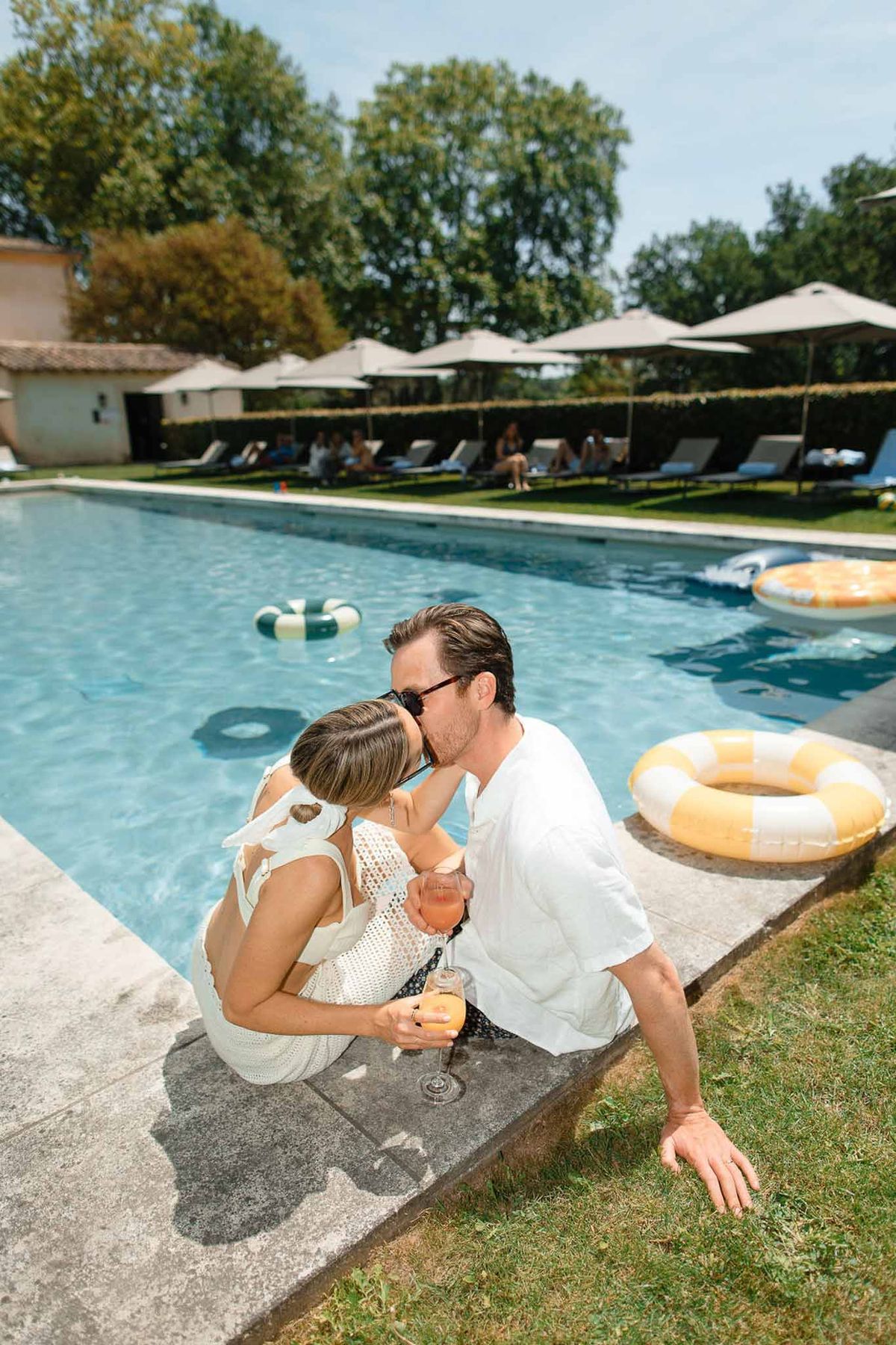 Bride and groom kissing at poolside during wedding reception at luxury resort venue