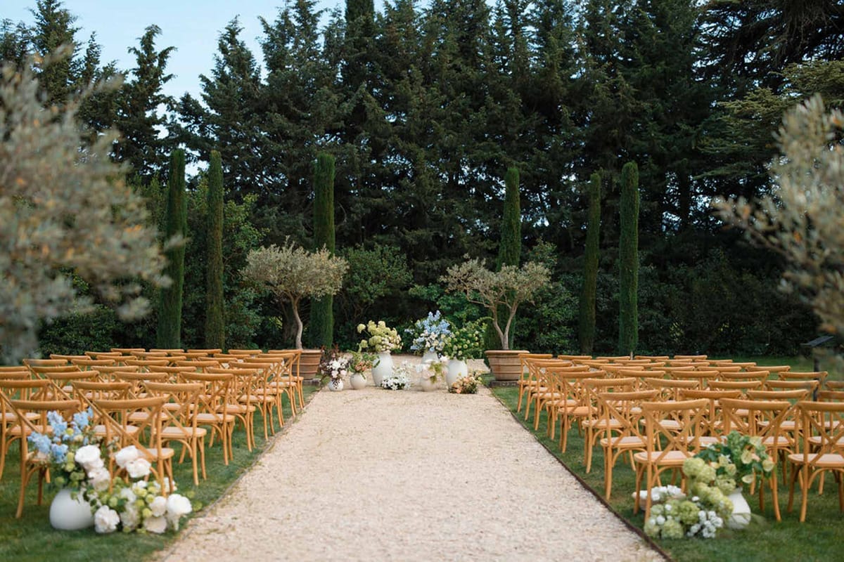Outdoor wedding ceremony setup with wooden chairs and floral arrangements in Mediterranean garden setting