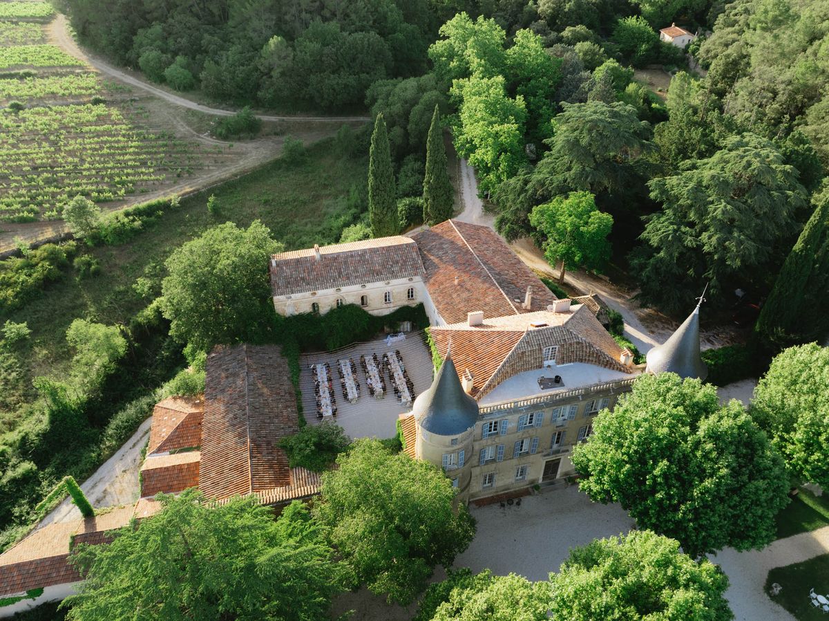 Aerial view of outdoor chateau courtyard wedding reception with long banquet tables and 80-100 guests