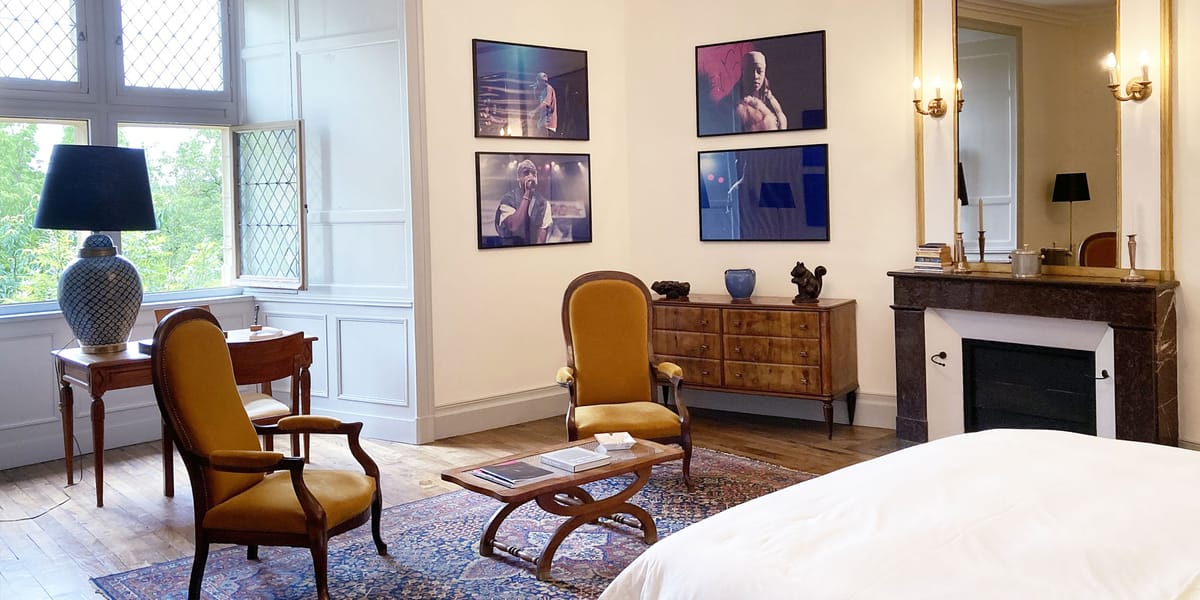 Chateau guest room with mustard velvet chairs, dark marble fireplace, and contemporary concert art