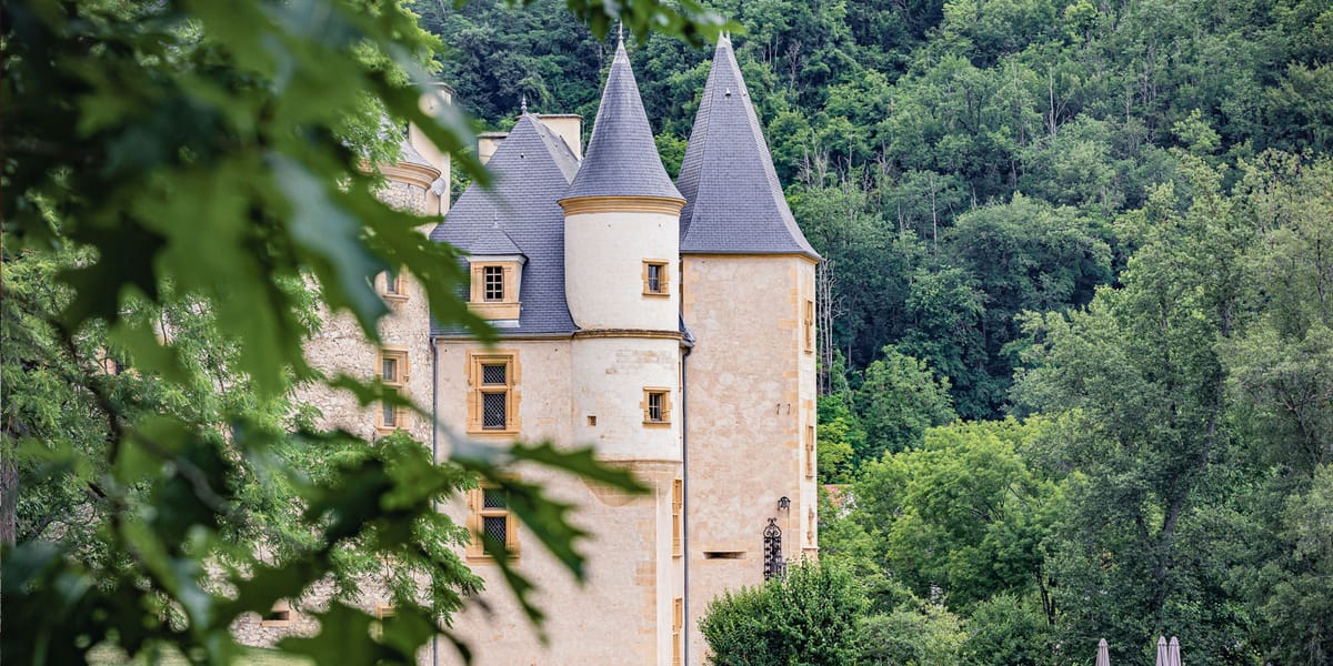 French chateau with cream limestone walls, golden stone window surrounds, and slate-grey conical turrets