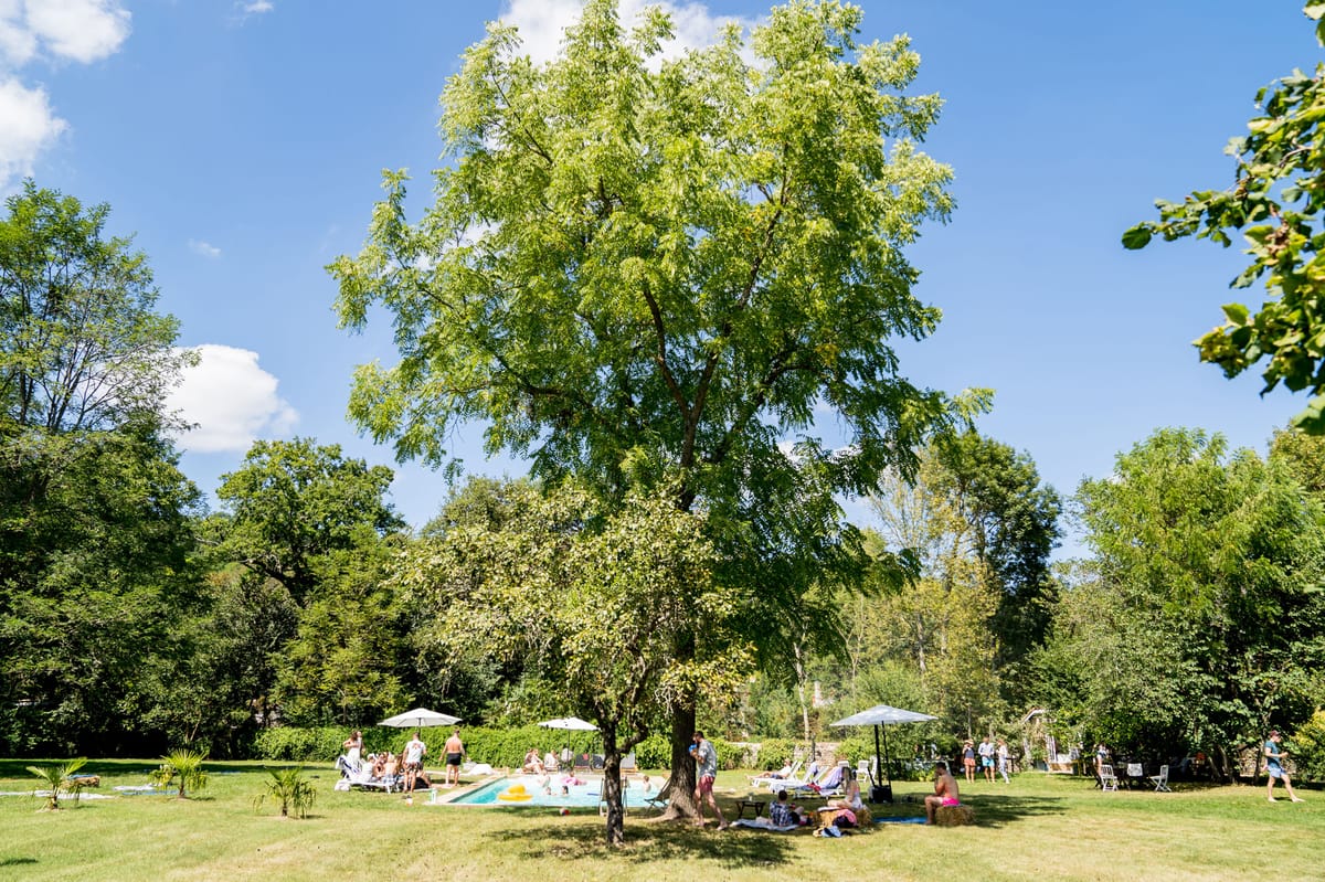 Garden pool party with guests on sun loungers hay bales and inflatable toys on wide lawn