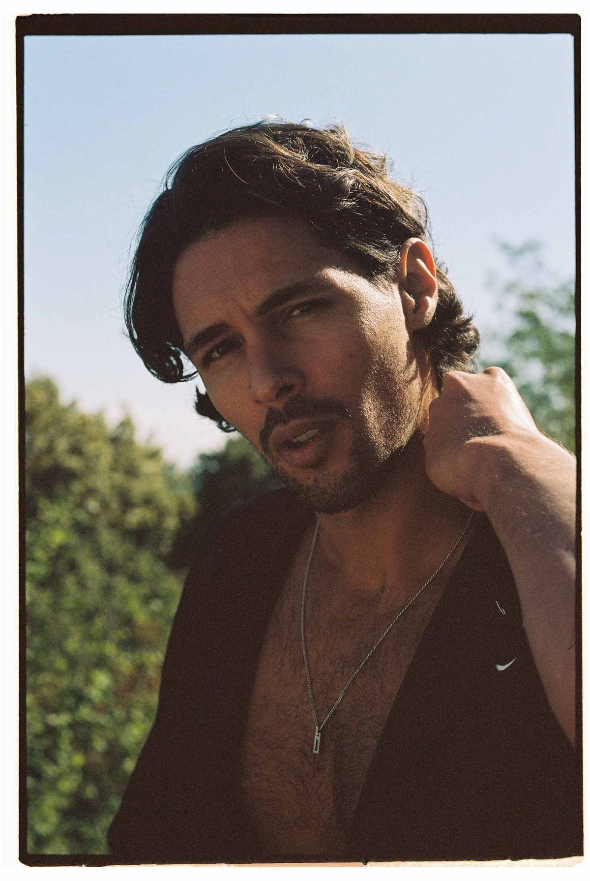Man in casual black top with silver chain necklace in outdoor portrait setting