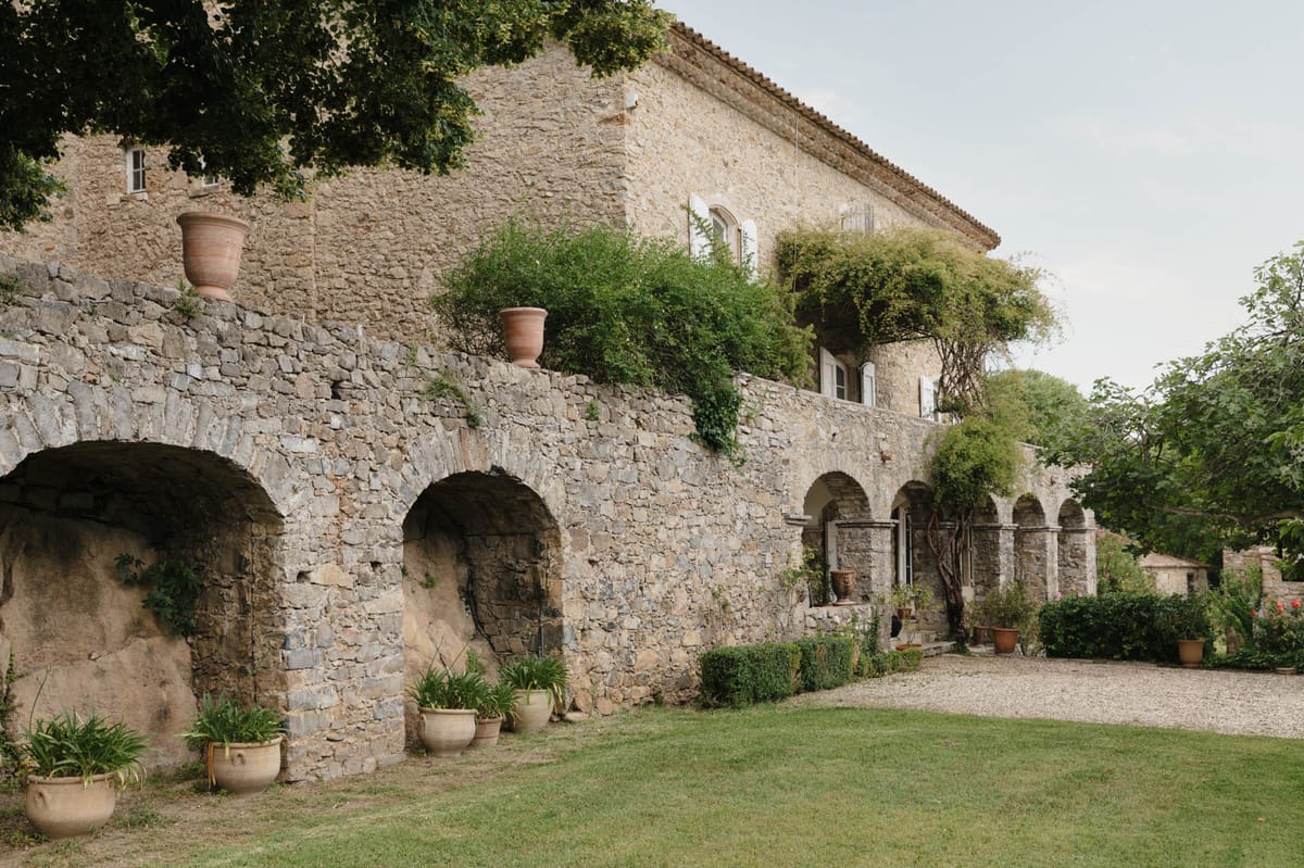Provencal stone mas with arched recesses arcaded loggia terracotta urns climbing plants and gravel driveway