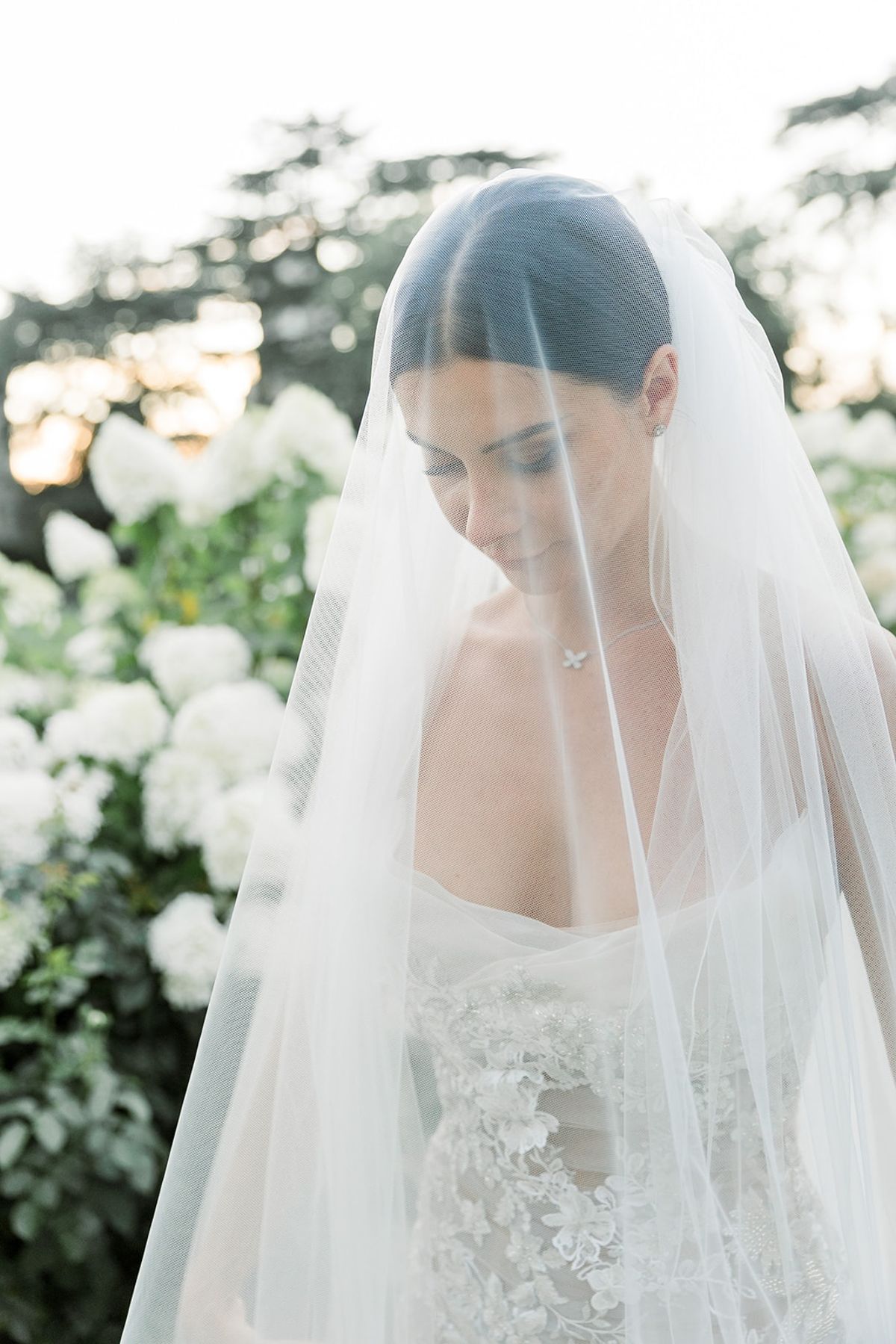 Bride in lace gown with veil draped over her head at Chateau Challain, Loire Valley