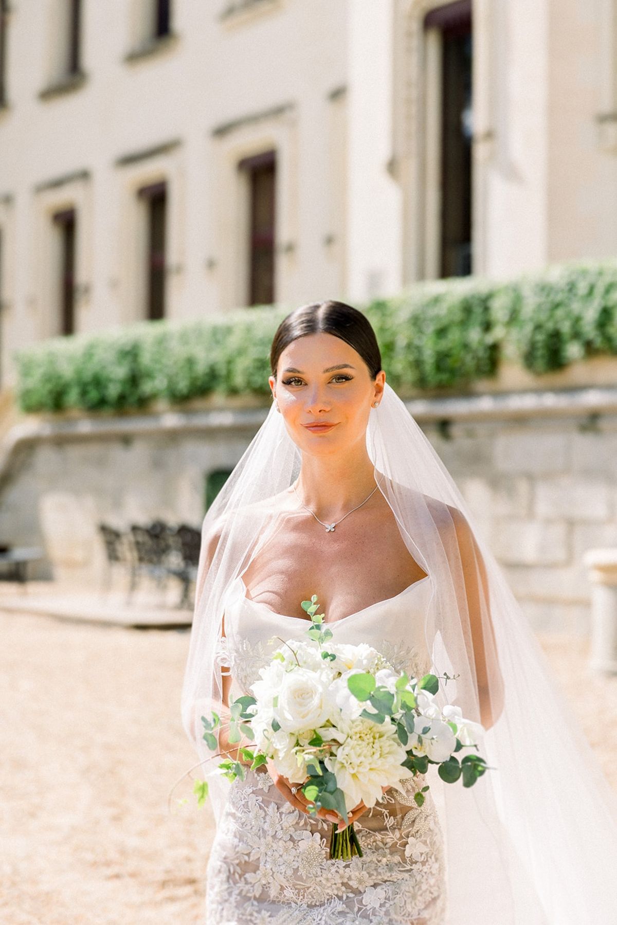 Bride holding white bouquet in lace gown at Chateau Challain, Loire Valley