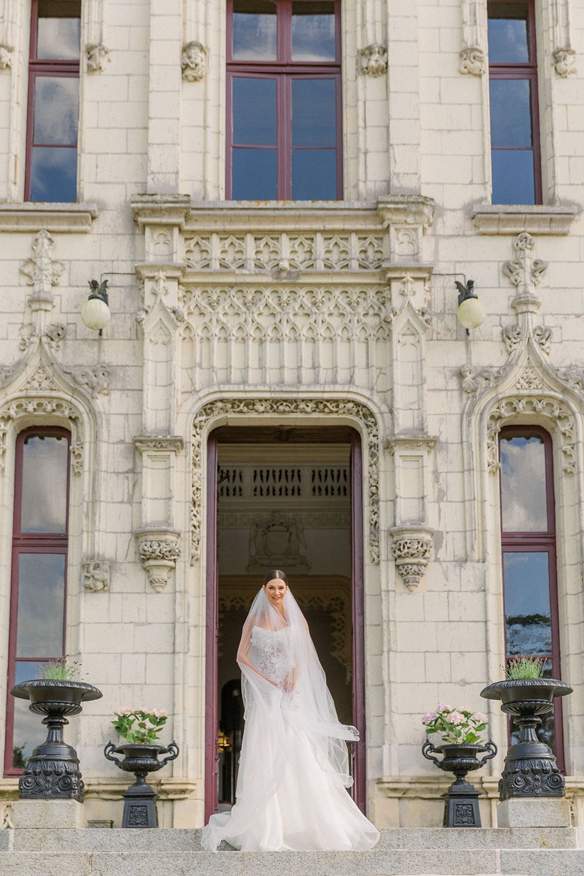 Bride in strapless gown at carved stone entrance of Chateau Challain, Loire Valley