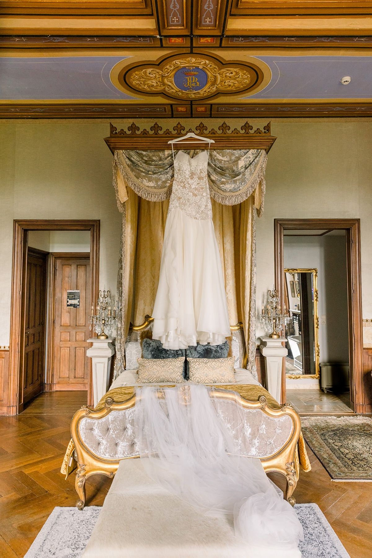 Wedding dress hanging in gilt canopy bedroom at Chateau Challain, Loire Valley