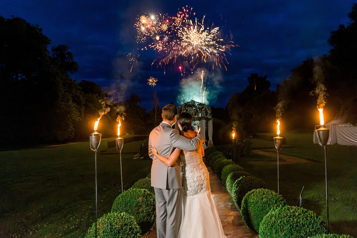 Couple watching fireworks above ceremony arch at Chateau Challain, Loire Valley