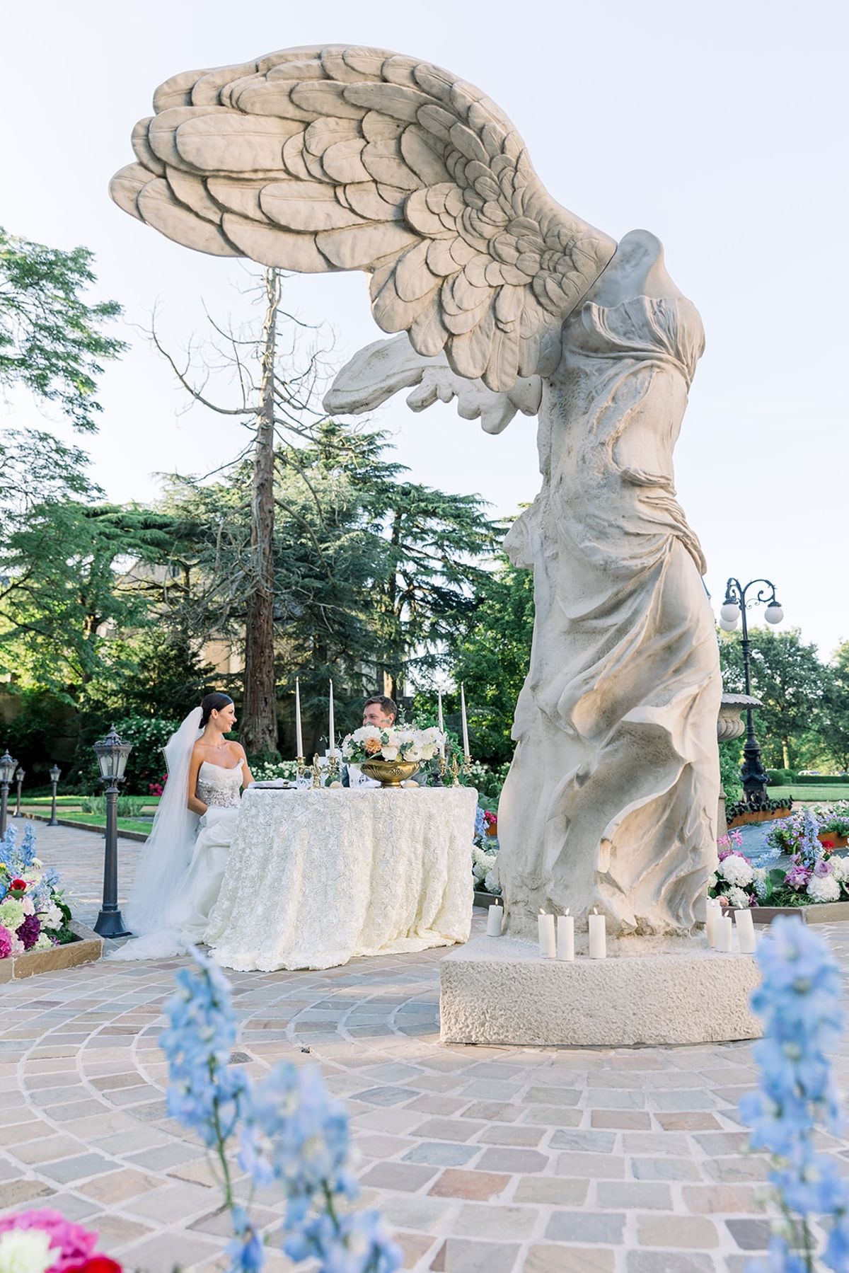 Couple at intimate dinner table beside winged statue at Chateau Challain, Loire Valley