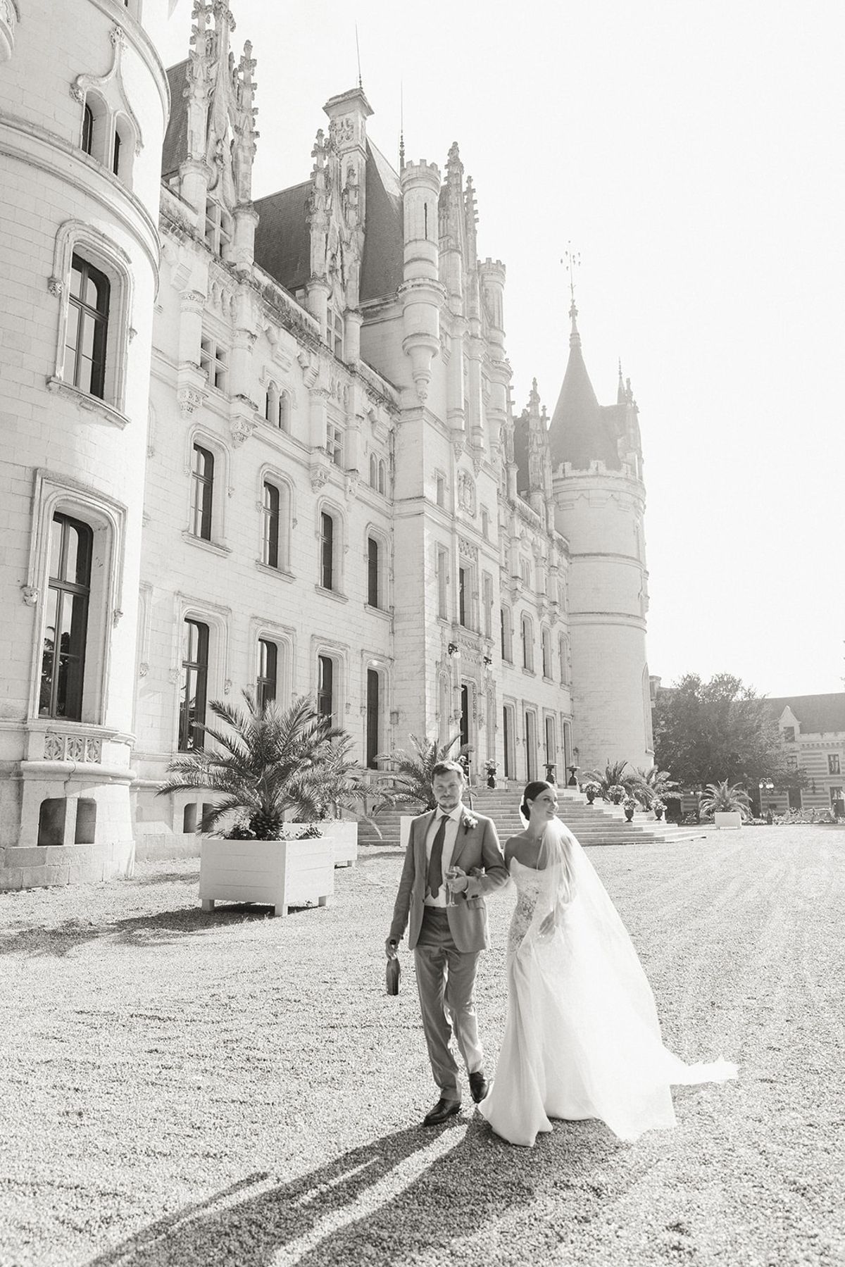 Couple walking past turreted chateau facade at Chateau Challain, Loire Valley