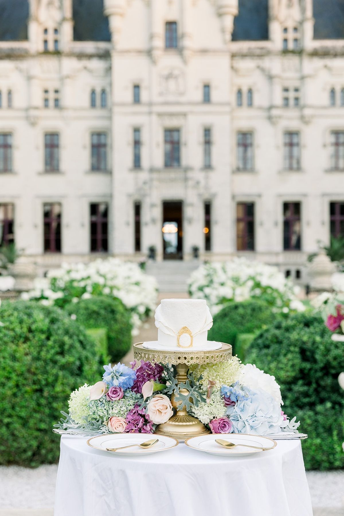 Wedding cake on gold pedestal with florals at Chateau Challain, Loire Valley